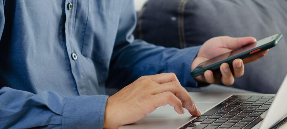 Personne face à un clavier avec un téléphone dans la main